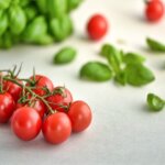 Une grappe de tomate cerise accompagné de feuille de basilic